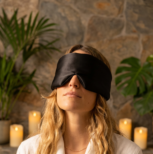 Person wearing a navy blue sleep mask against a gray background